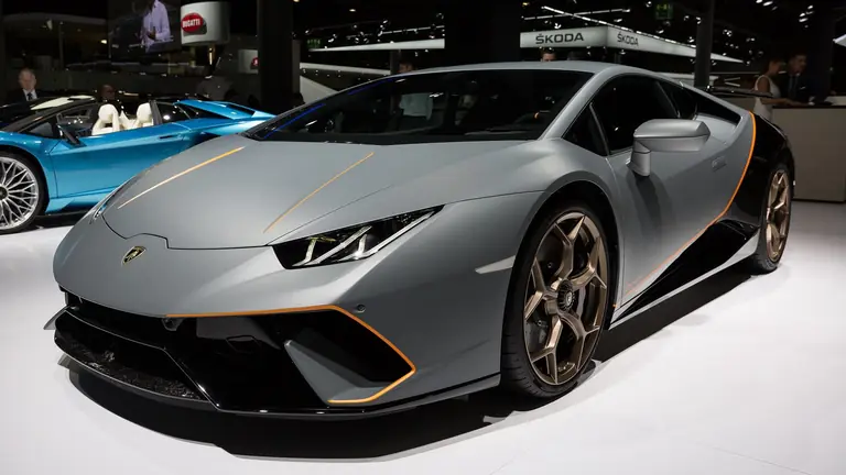 Grey Lamborghini Huracán Performante with bronze wheels and orange trim, front three-quarter view on a motor show stand